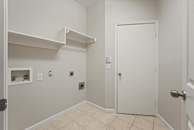 clothes washing area with electric dryer hookup, washer hookup, hookup for a gas dryer, light tile patterned flooring, and baseboards