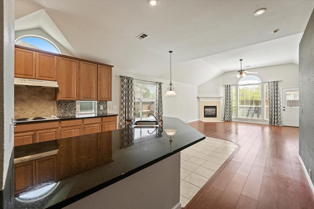 kitchen with vaulted ceiling, dark countertops, ceiling fan, under cabinet range hood, and white electric cooktop