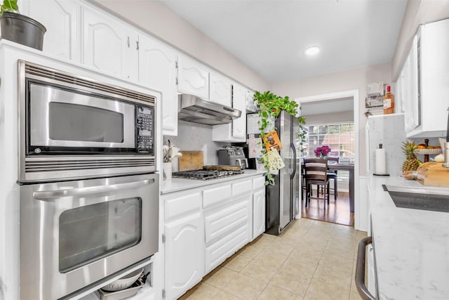 1032 Peach Ln, Desoto, TX 75115 - kitchen with appliances with stainless steel finishes, under cabinet range hood, light countertops, light tile patterned flooring, and white cabinets