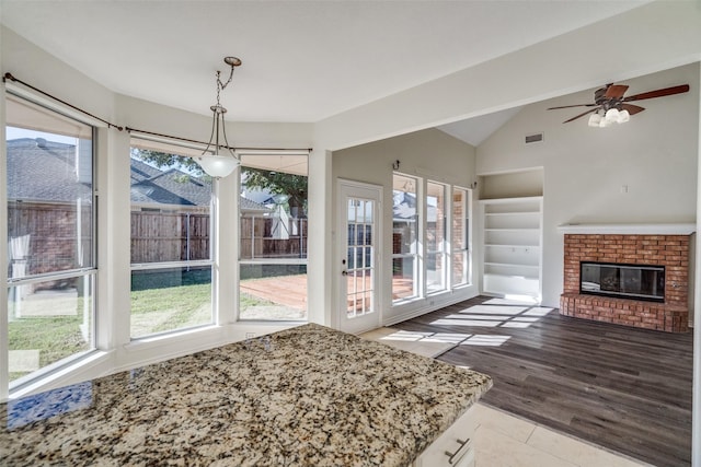 4804 Nocona Dr, Plano, TX 75024 - unfurnished dining area featuring lofted ceiling, a fireplace, ceiling fan, and wood finished floors