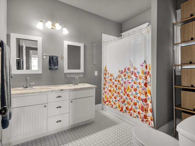 1942 Fairmount Ave, Fort Worth, TX 76110 - bathroom featuring toilet, double vanity, tile patterned floors, and baseboards