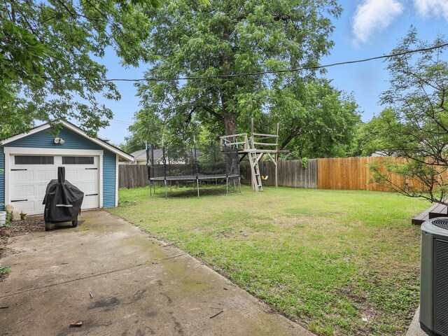 1942 Fairmount Ave, Fort Worth, TX 76110 - view of yard featuring a trampoline, driveway, an outbuilding, a garage, and central AC