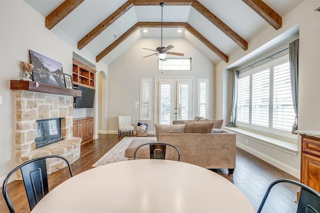 4701 Trevor Trl, Grapevine, TX 76051 - living area featuring a ceiling fan, dark wood-style flooring, a stone fireplace, beam ceiling, and high vaulted ceiling
