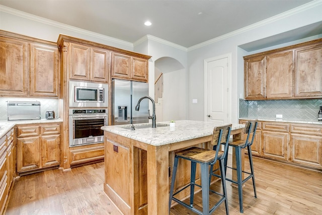 4701 Trevor Trl, Grapevine, TX 76051 - kitchen featuring appliances with stainless steel finishes, a sink, light wood finished floors, decorative backsplash, and ornamental molding