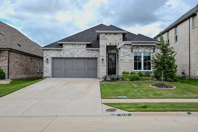 french provincial home with roof with shingles, an attached garage, a front lawn, stone siding, and concrete driveway