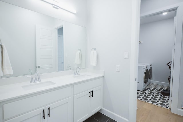 full bathroom with independent washer and dryer, baseboards, double vanity, and wood finished floors