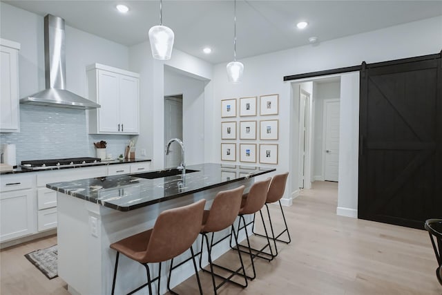 kitchen with wall chimney exhaust hood, gas stovetop, a sink, light wood-style floors, and recessed lighting