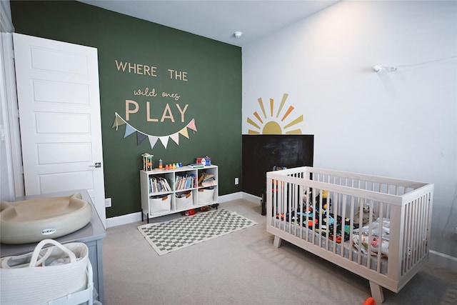 carpeted bedroom with a crib and baseboards