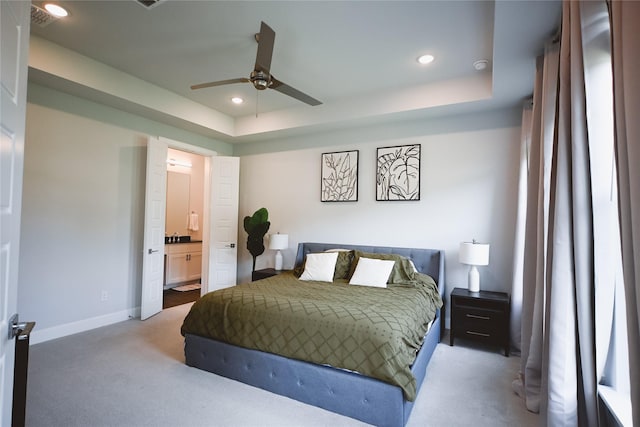 bedroom featuring carpet floors, a tray ceiling, connected bathroom, baseboards, and recessed lighting