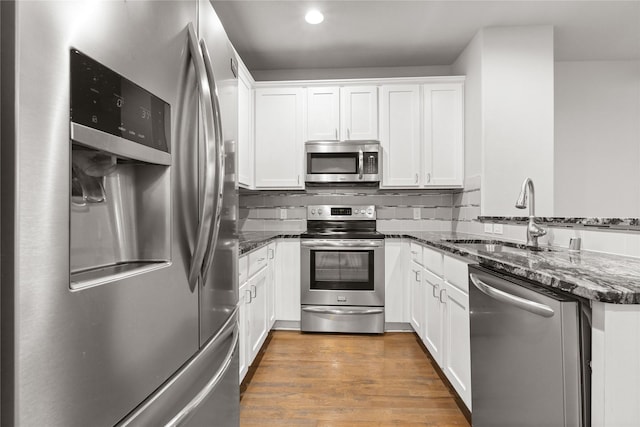 1317 Palm Canyon Dr, Dallas, TX 75204 - kitchen with stainless steel appliances, a sink, a peninsula, dark stone counters, and recessed lighting