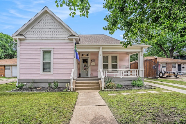 view of front of property with a porch, a front lawn, and a shingled roof