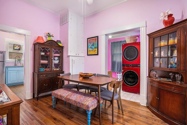 dining space with stacked washer / dryer, ornamental molding, and wood finished floors