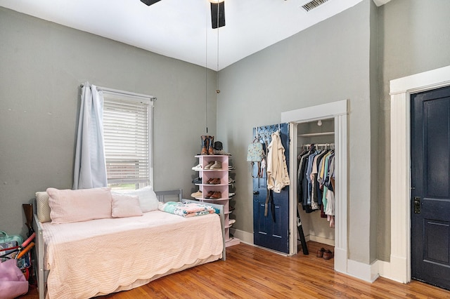 bedroom with wood finished floors, a closet, baseboards, and a ceiling fan