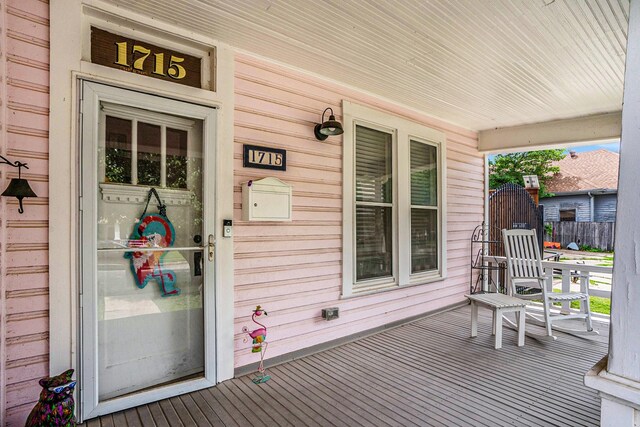wooden deck featuring a porch and fence