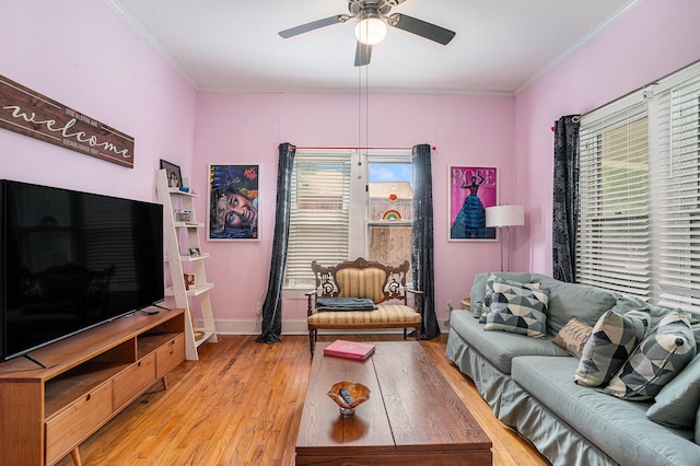 living area featuring light wood-type flooring, a ceiling fan, ornamental molding, and baseboards