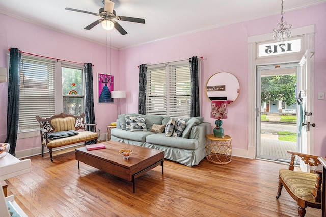 living area with light wood-type flooring, ceiling fan, plenty of natural light, crown molding, and baseboards