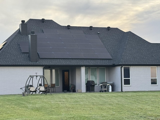 252 Harvard Ln, Springtown, TX 76082 - rear view of house with a shingled roof, a chimney, brick siding, and solar panels