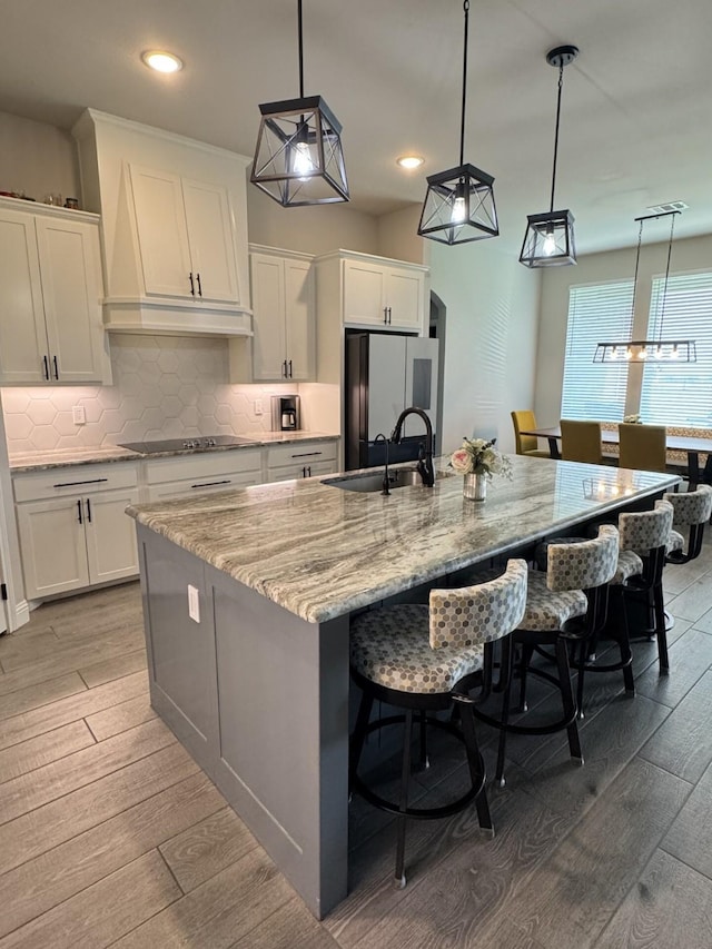 252 Harvard Ln, Springtown, TX 76082 - kitchen with refrigerator, premium range hood, a large island with sink, white cabinets, and black electric cooktop