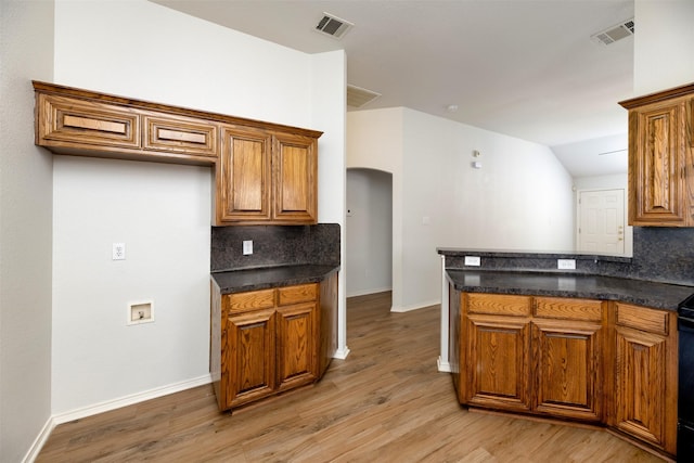 4541 Grainland Ct, Fort Worth, TX 76179 - kitchen with arched walkways, brown cabinetry, and tasteful backsplash