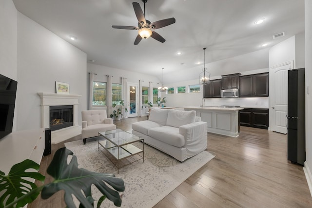 5604 Ridgeson Dr, Mckinney, TX 75071 - living area featuring recessed lighting, a chandelier, ceiling fan, a fireplace with raised hearth, and light wood-style flooring