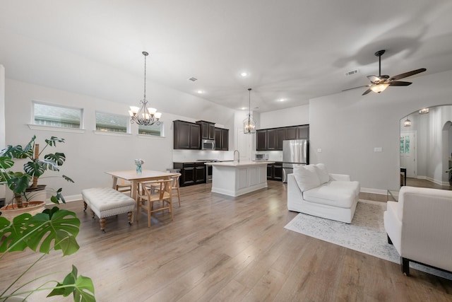 5604 Ridgeson Dr, Mckinney, TX 75071 - living room featuring a chandelier, arched walkways, light wood-type flooring, ceiling fan, and baseboards