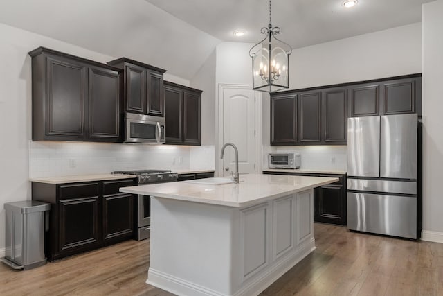 5604 Ridgeson Dr, Mckinney, TX 75071 - kitchen featuring appliances with stainless steel finishes, a sink, a chandelier, light wood finished floors, and lofted ceiling