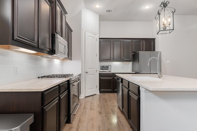 5604 Ridgeson Dr, Mckinney, TX 75071 - kitchen featuring appliances with stainless steel finishes, a sink, dark brown cabinetry, light wood finished floors, and light countertops