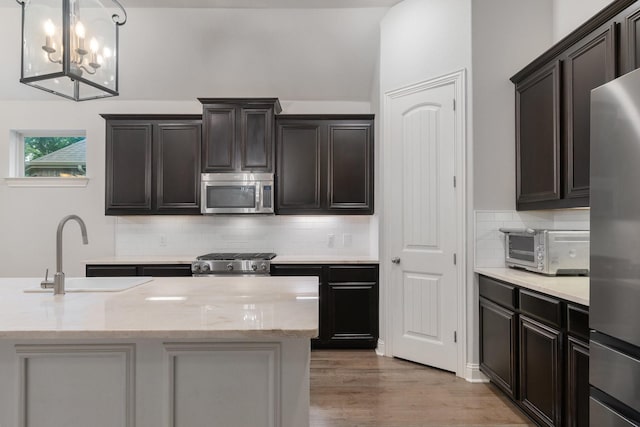 5604 Ridgeson Dr, Mckinney, TX 75071 - kitchen with appliances with stainless steel finishes, a sink, hanging light fixtures, wood finished floors, and decorative backsplash