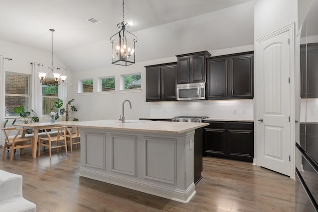 5604 Ridgeson Dr, Mckinney, TX 75071 - kitchen featuring stainless steel microwave, a chandelier, lofted ceiling, light countertops, and wood finished floors