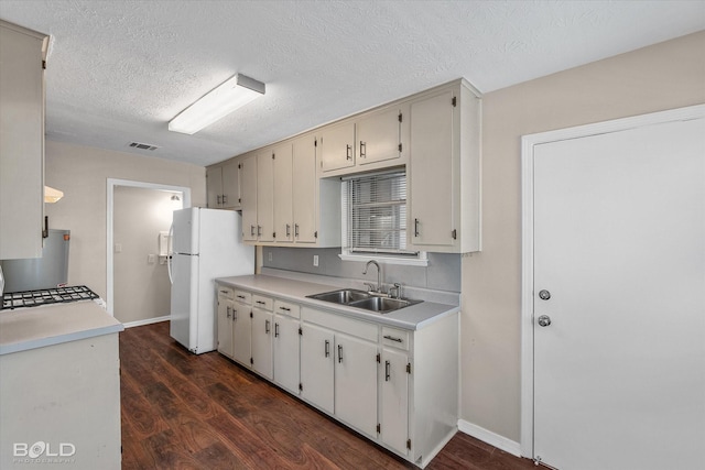 kitchen featuring a sink, freestanding refrigerator, dark wood-style floors, light countertops, and a textured ceiling