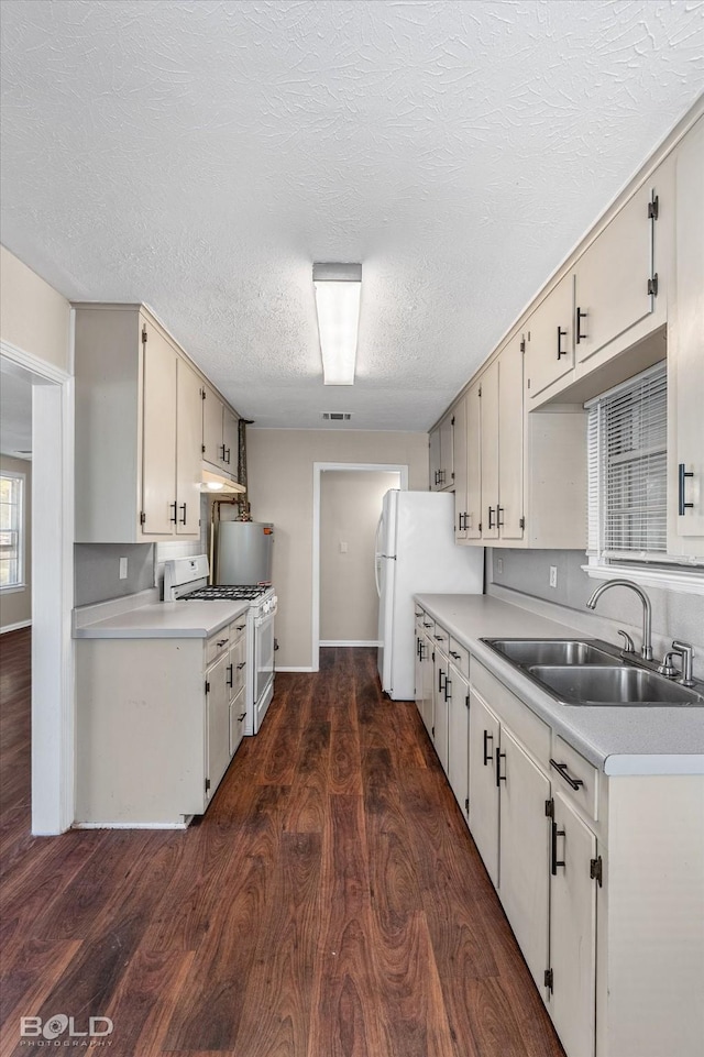 kitchen featuring white appliances, a sink, light countertops, dark wood-style flooring, and a textured ceiling