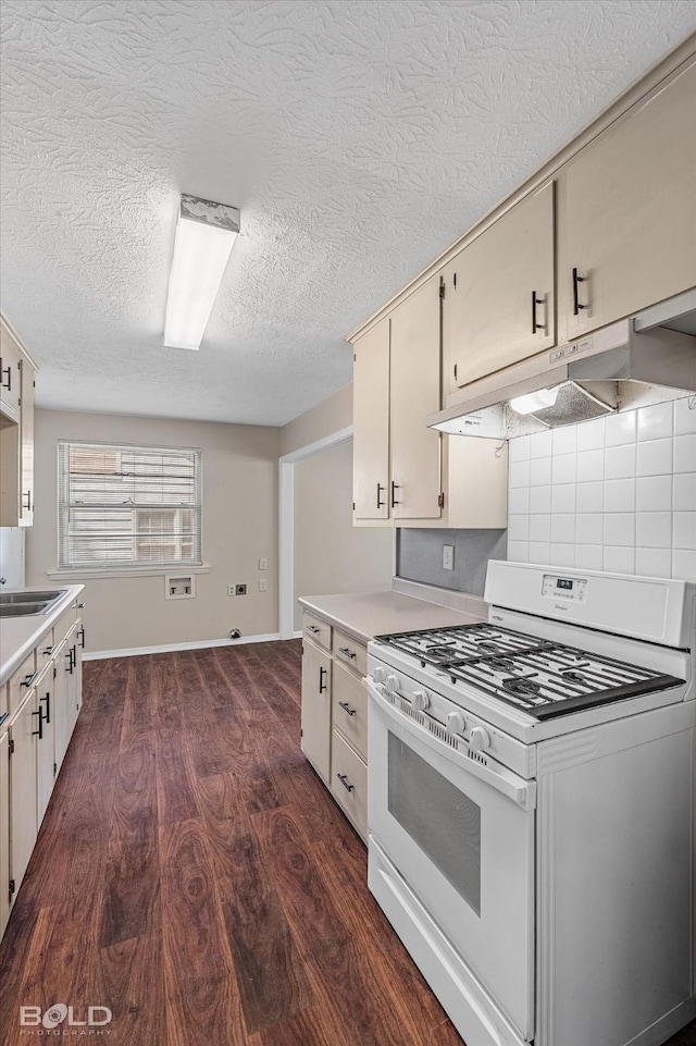 kitchen with gas range gas stove, under cabinet range hood, light countertops, dark wood-style flooring, and a textured ceiling