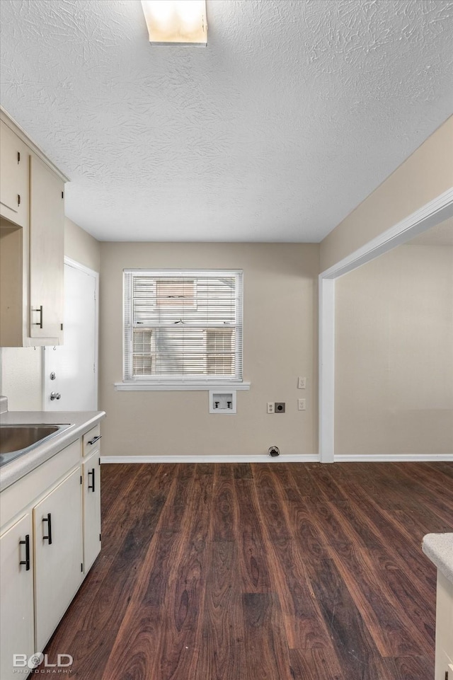kitchen with dark wood-type flooring, baseboards, light countertops, a textured ceiling, and a sink