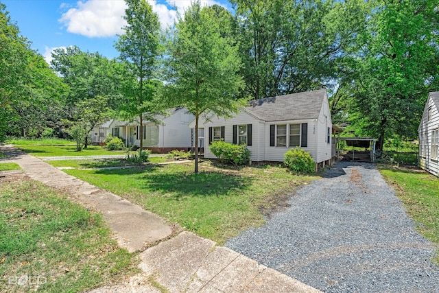 view of front of house featuring a front yard, driveway, a shingled roof, and a detached carport