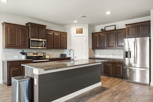 kitchen with appliances with stainless steel finishes, a sink, light wood-type flooring, dark brown cabinetry, and recessed lighting