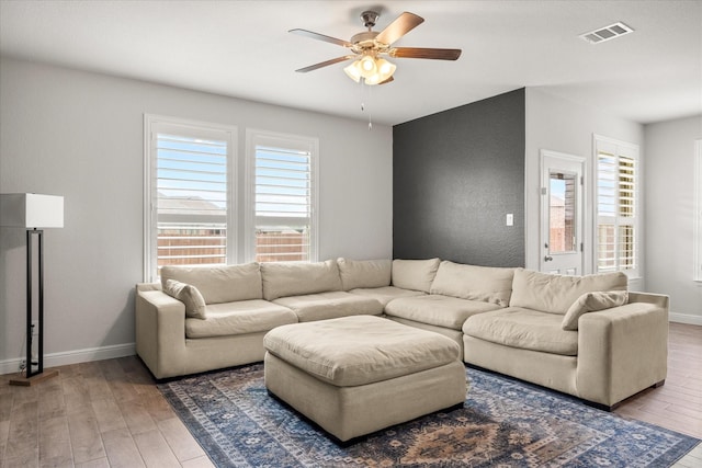 living area featuring ceiling fan, hardwood / wood-style flooring, and baseboards