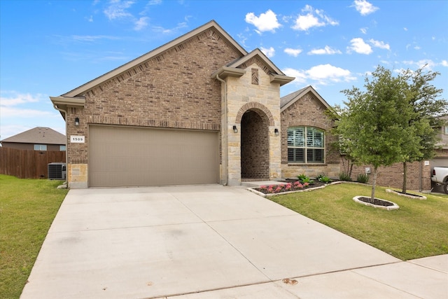 french country home featuring central air condition unit, a garage, concrete driveway, and brick siding