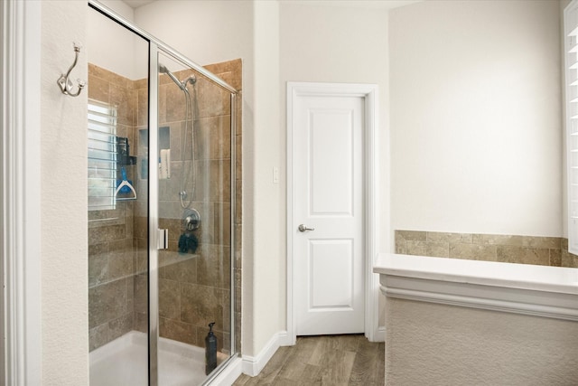 bathroom with wood finished floors and a shower stall