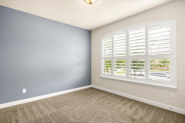 carpeted empty room featuring baseboards