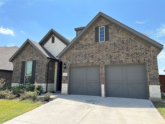 french provincial home with brick siding, driveway, a garage, and stone siding