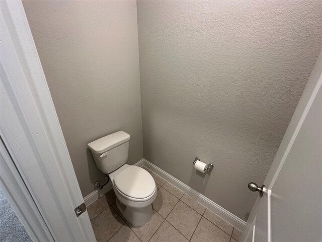 bathroom featuring toilet, tile patterned flooring, and baseboards