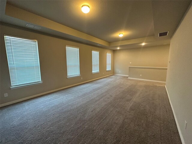 unfurnished room with a tray ceiling, baseboards, and carpet