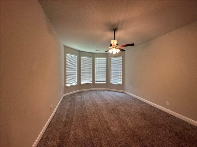 carpeted spare room featuring baseboards, ceiling fan, and a textured ceiling