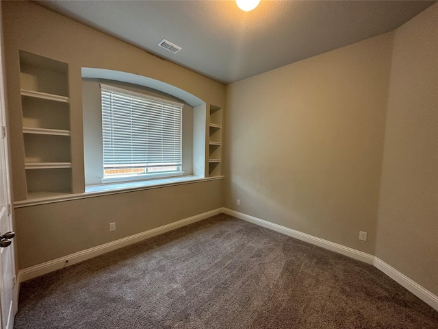 empty room with carpet flooring, built in features, and baseboards