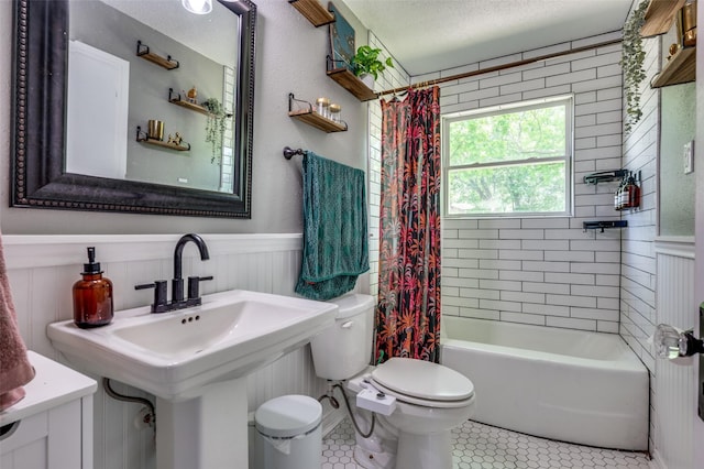2420 N Carroll Blvd, Denton, TX 76201 - bathroom featuring toilet, tile patterned floors, wainscoting, a textured ceiling, and shower / bathtub combination with curtain