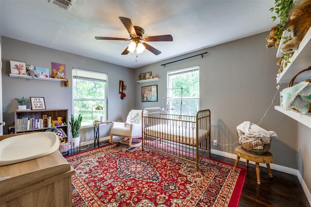 2420 N Carroll Blvd, Denton, TX 76201 - bedroom with baseboards, wood finished floors, a nursery area, a textured ceiling, and ceiling fan