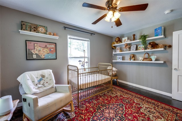2420 N Carroll Blvd, Denton, TX 76201 - bedroom featuring wood finished floors, a crib, baseboards, and a ceiling fan