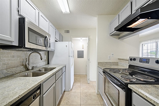 kitchen with appliances with stainless steel finishes, a sink, under cabinet range hood, decorative backsplash, and a textured ceiling