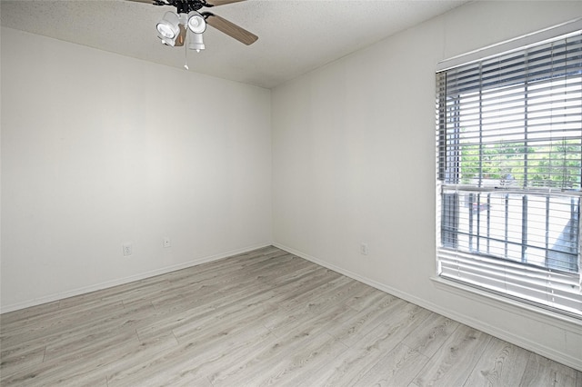 spare room featuring a ceiling fan, light wood-style floors, and baseboards