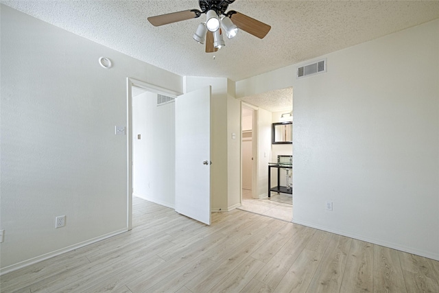 spare room with a textured ceiling, light wood-style flooring, ceiling fan, and baseboards